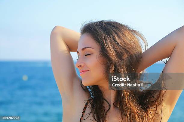 Beautiful Woman Relaxing With Closed Eyes On Blue Sea Background Stock Photo - Download Image Now