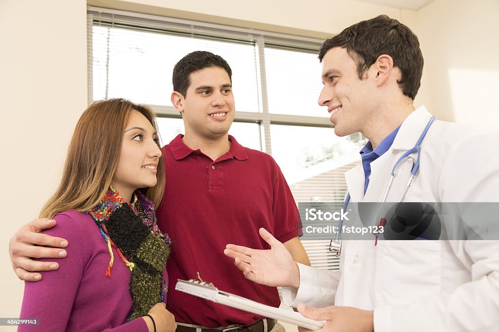 Medical: Doctor discussing test results with patients. Young couple. Hospital. A doctor with his young couple patients.  He is discussing test results.  Adult Stock Photo