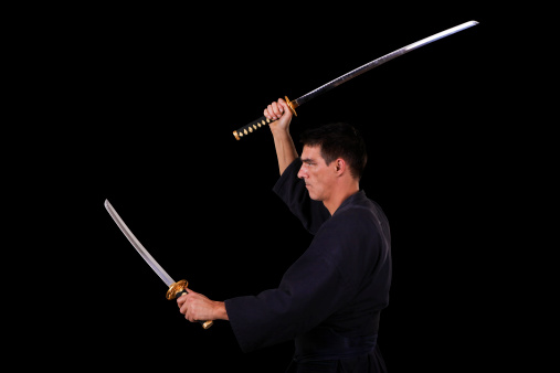 Adult man exercising kendo with katanas in nito position