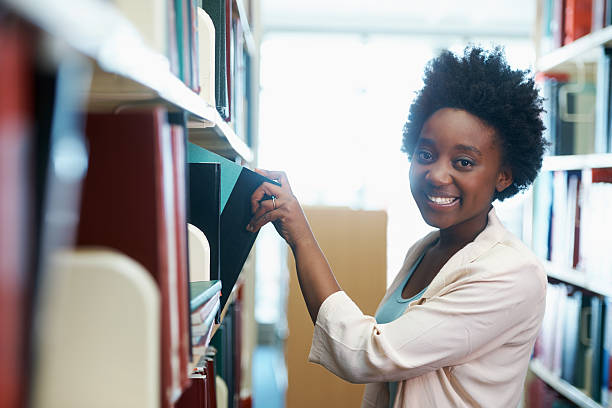Working on her thesis A young woman selecting some books in the library dissertation stock pictures, royalty-free photos & images