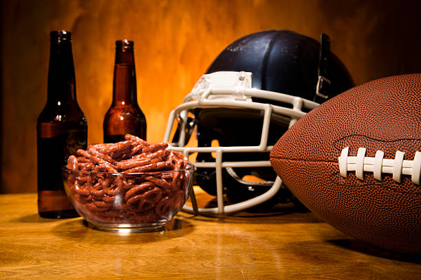Sports:  Football helmet, ball on table.  Pretzels and beer. championship game. Football sports helmet and football on table with pretzels and beer. championship game party! beer bottle photos stock pictures, royalty-free photos & images