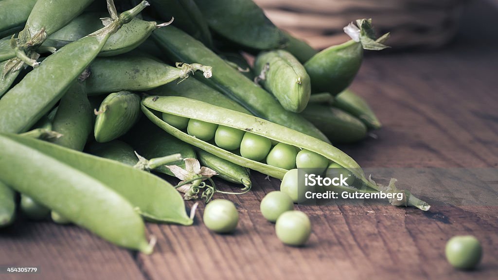 Pea pods with Basket fresh Pea pods and Pea on a wooden Table with Basket Basket Stock Photo