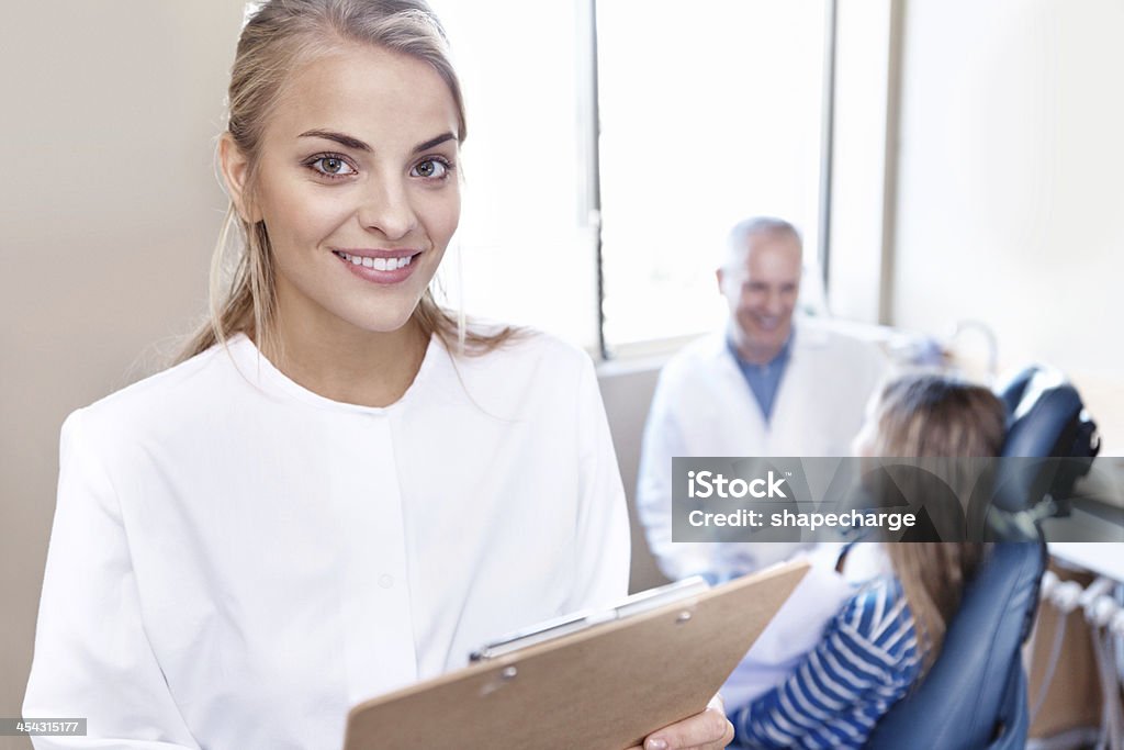 Does your medical insurance cover dentistry? A young girl sitting in the dentist's chair while a lovely dental hygienist stands in the foreground Adult Stock Photo