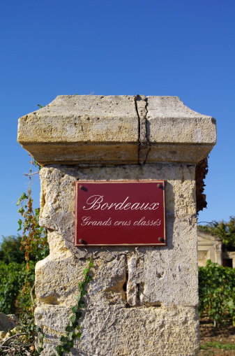 Street sign: grand crus classes, with wine in background. Bordeaux, Gironde, France