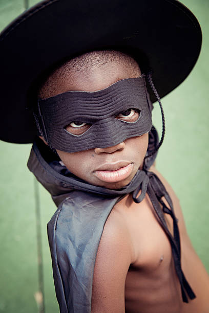 Very expressive little black boy costumed as Zorro playing outside. 