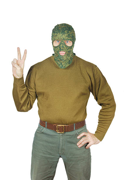 homem usa máscara de camuflagem verde e mostra sinal da vitória - pants green camouflage men - fotografias e filmes do acervo