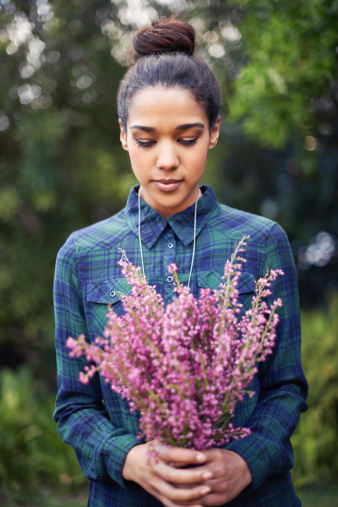 A young woman holding a bunch of flowers in a garden