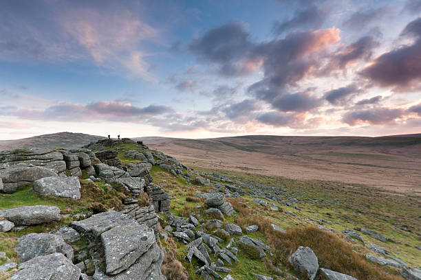 Oke Tor Dartmoor in Devon with two walkers on top I was waiting for the sunset looking towards Oke Tor on Dartmoor when two walkers stood on top and made the image. The shot looks south towards the central wilderness. dartmoor photos stock pictures, royalty-free photos & images
