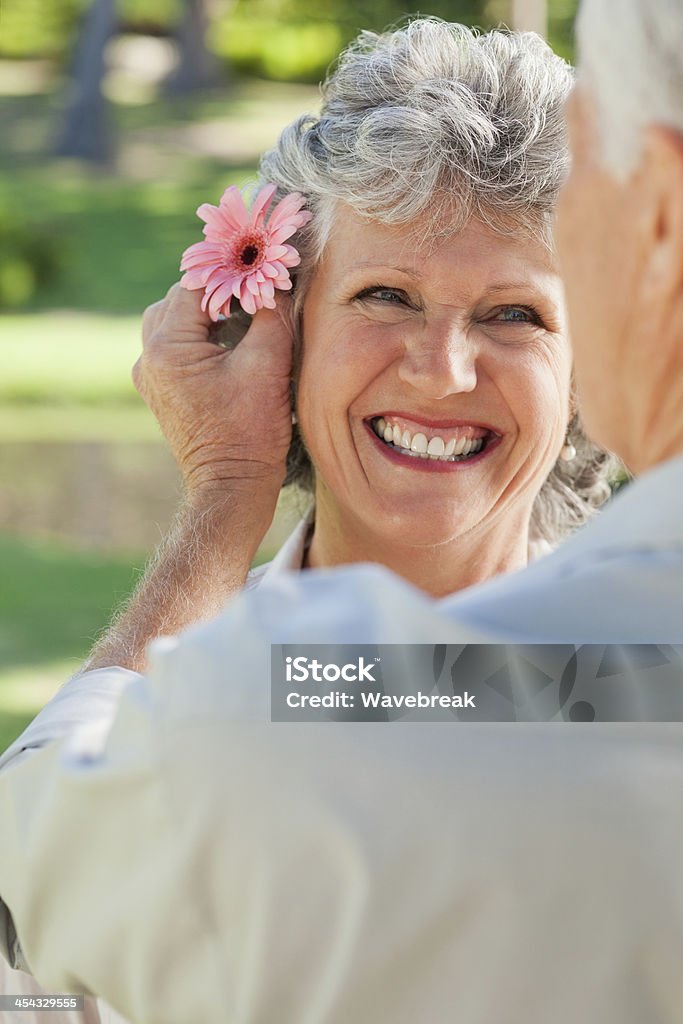 Wife smiles while husband puts flower in her hair A wife smiling at her husband and he puts a flower in her hair 50-59 Years Stock Photo