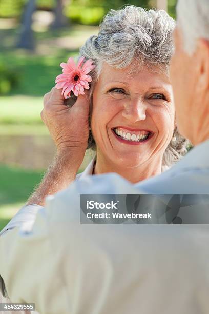 Wife Smiles While Husband Puts Flower In Her Hair Stock Photo - Download Image Now - 50-59 Years, 60-69 Years, Active Seniors