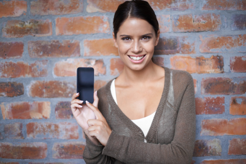 Portrait of a young woman holding up the blank screen of her smartphone to the camera