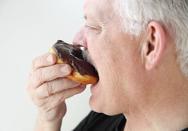 istock man takes bite of doughnut 454332687
