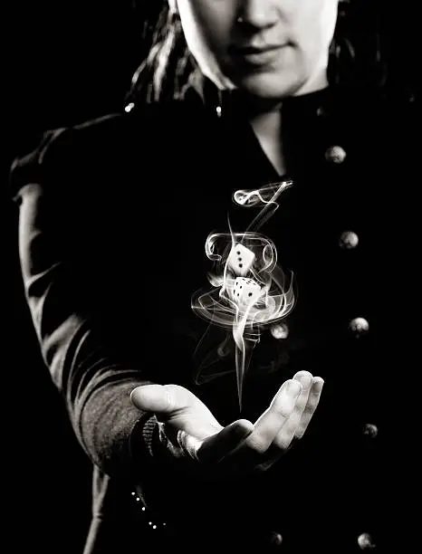 Concept black and white shot of a young woman tossing up dice in a swirl of smoke. Good or bad fortune, it's a toss-up or the luck of the throw, and your dreams might go up in smoke!