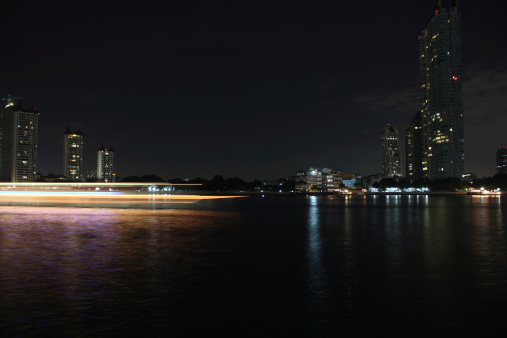 Buildings along the river at night. View from Asiatique. Attractions in Bangkok, Thailand.