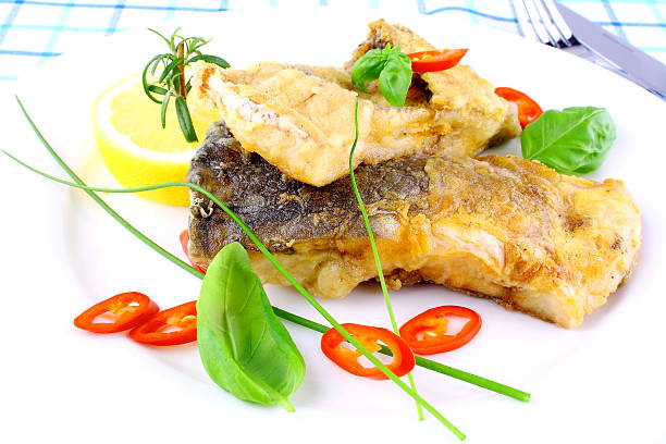 istock Fried fish fillets, lemon, chili peppers slice on white plate 454337317