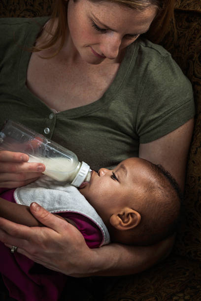 istock mother bottle feeding multi-ethnic adopted baby daughter 454338425