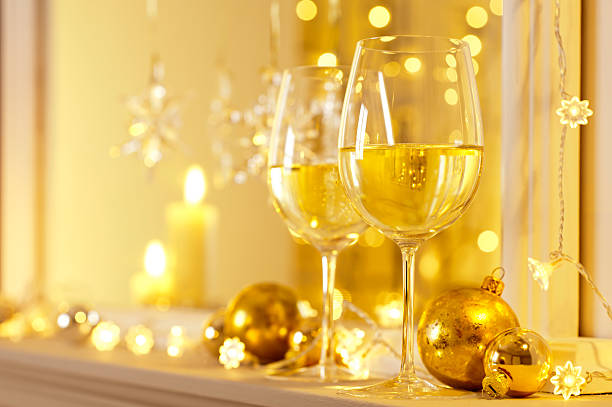 2 blue wine glasses on a red tablecloth, decorated with silver Christmas balls. The wine-glasses stand on their heads and are filled with colorful Christmas balls. Each wine glass carries a red tea light holder.
