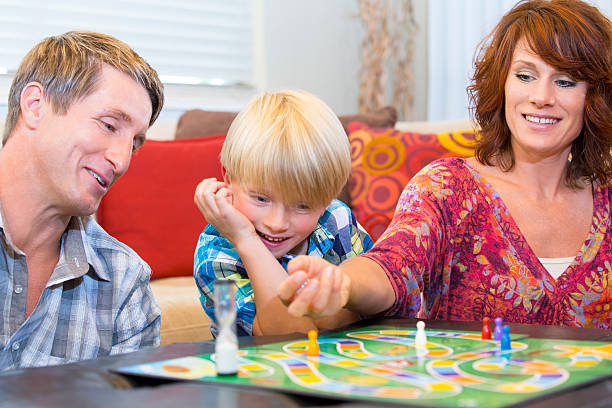 istock Little boy playing a fun board game with his parents 454338591
