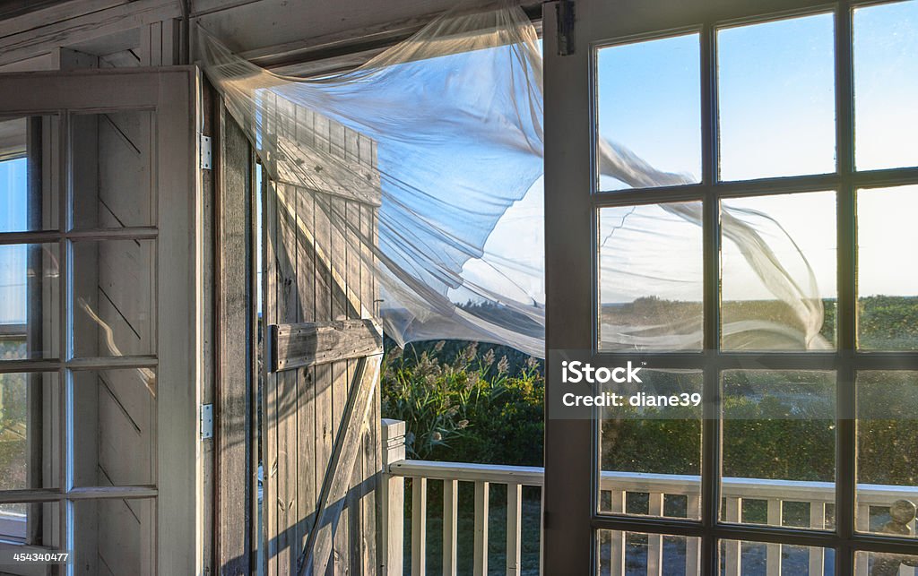 Morning Breeze at the Beach House A breeze blows a curtain in the doorway of an old New England beach house. Wind Stock Photo