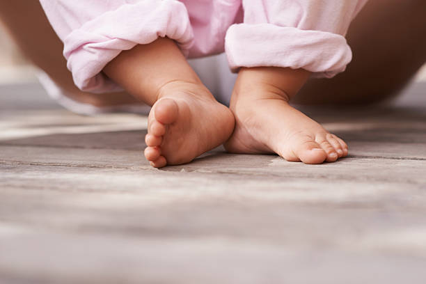 Closeup image of a baby's feet as she sits outside with her mother