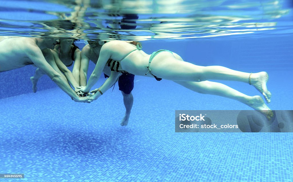 friends in pool young friends in swimming pool holding hands 25-29 Years Stock Photo