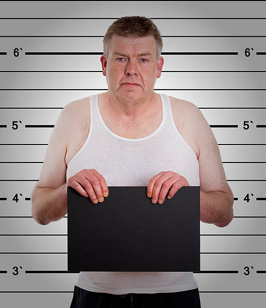 istock mugshot - young man arrested and  holding a  blackboard 454346125