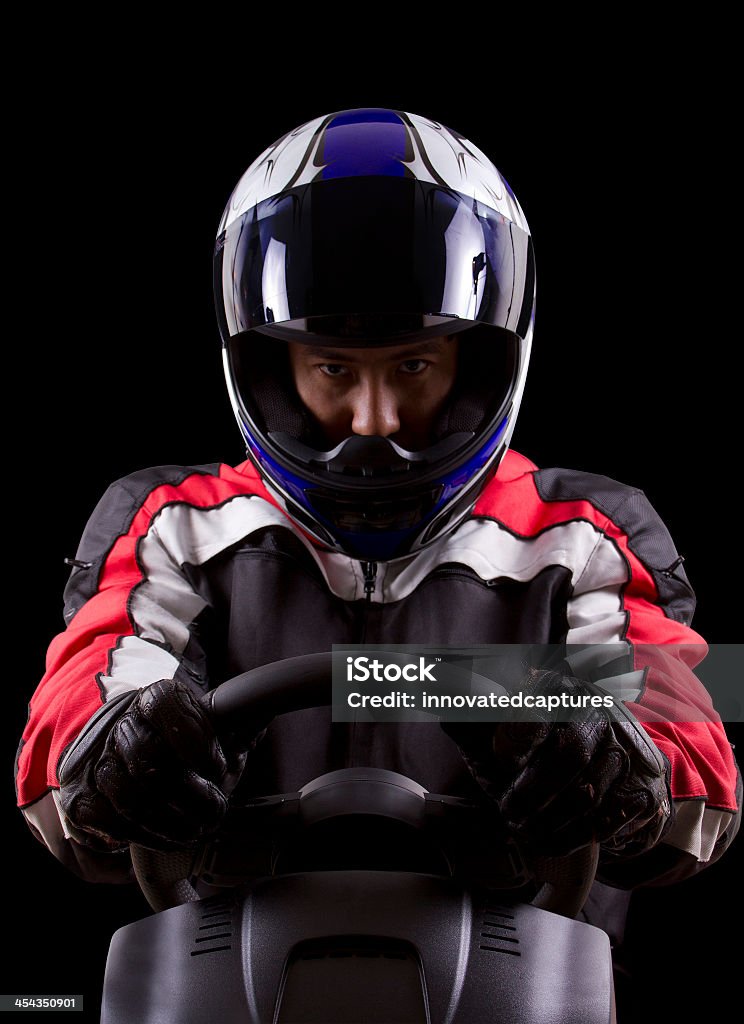 Dramatic portrait of a race car driver racerwearing red racing suit and blue helmet on a steering wheel Piloting Stock Photo