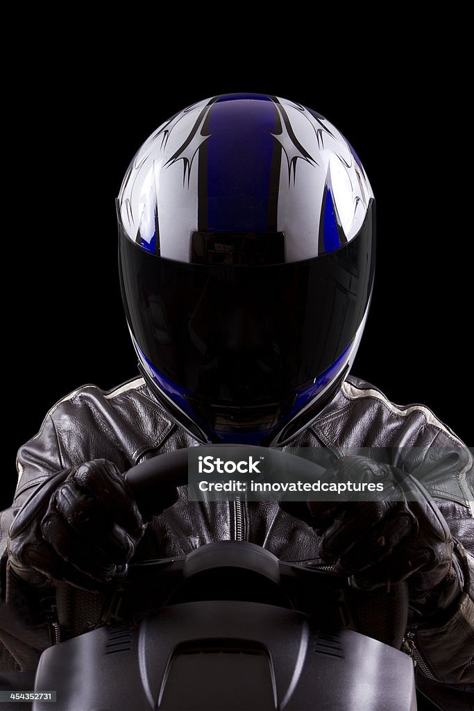 Racer Wearing a Helmet and Leather Protective Gear racerwearing leather racing suit and blue helmet on a steering wheel Helmet Stock Photo