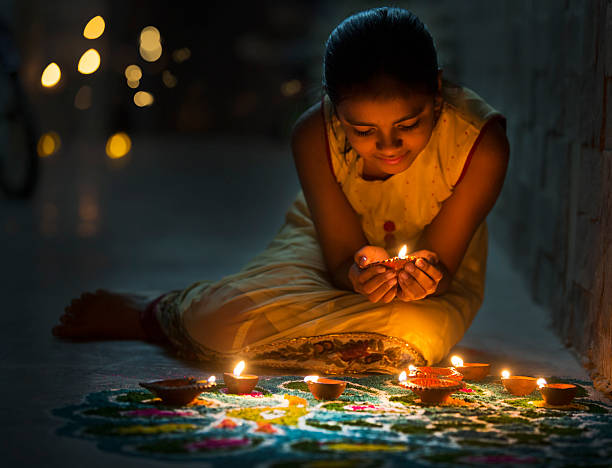Girl making Rangoli and decorating with Oil lamps for Diwali stock photo