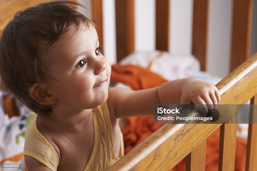 She wants out of the crib! A cute little girl standing up in her crib 12-17 Months Stock Photo