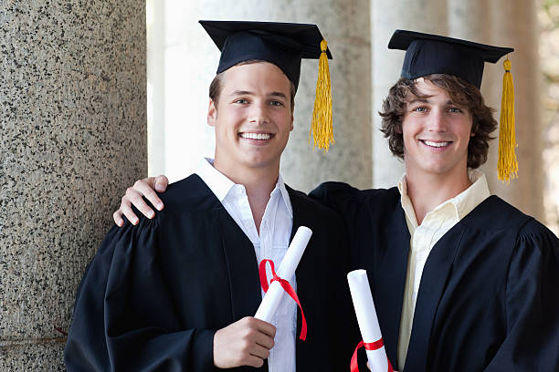 istock Two happy graduates males holding their diploma while posing 454354273