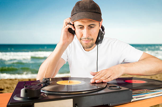 DJ mixing vinyl record on a  turntable DJ mixing vinyl record on a  turntable with beach  background dubstep photos stock pictures, royalty-free photos & images