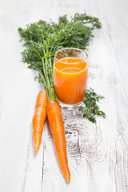 istock Carrot juice with fresh carrots on white table 454356961