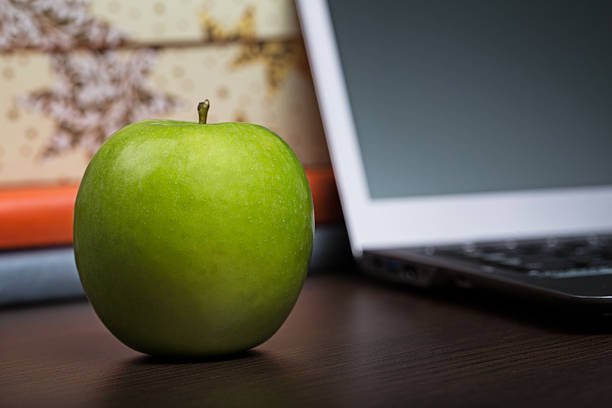 istock Green apple on wooden office desk 454357293
