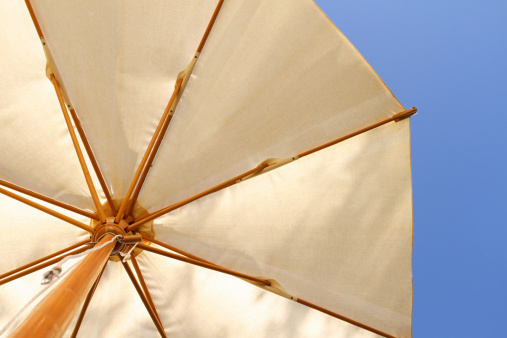 Sunshade awnings tent with sky and trees. Beige parasol in summer sunshine