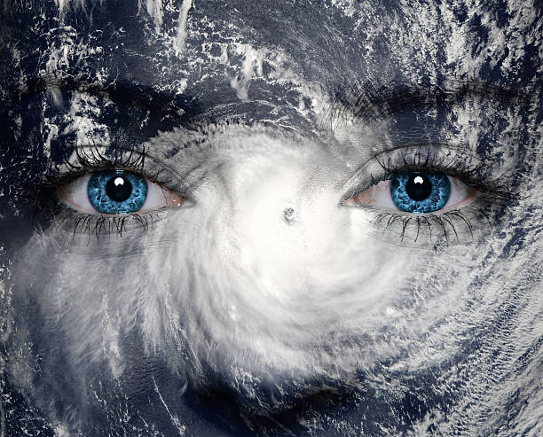 A close-up of a woman's face with blue eyes and nature A blue eye in the middle of a tropical hurricane. Elements of this image furnished by NASA storm system stock pictures, royalty-free photos & images