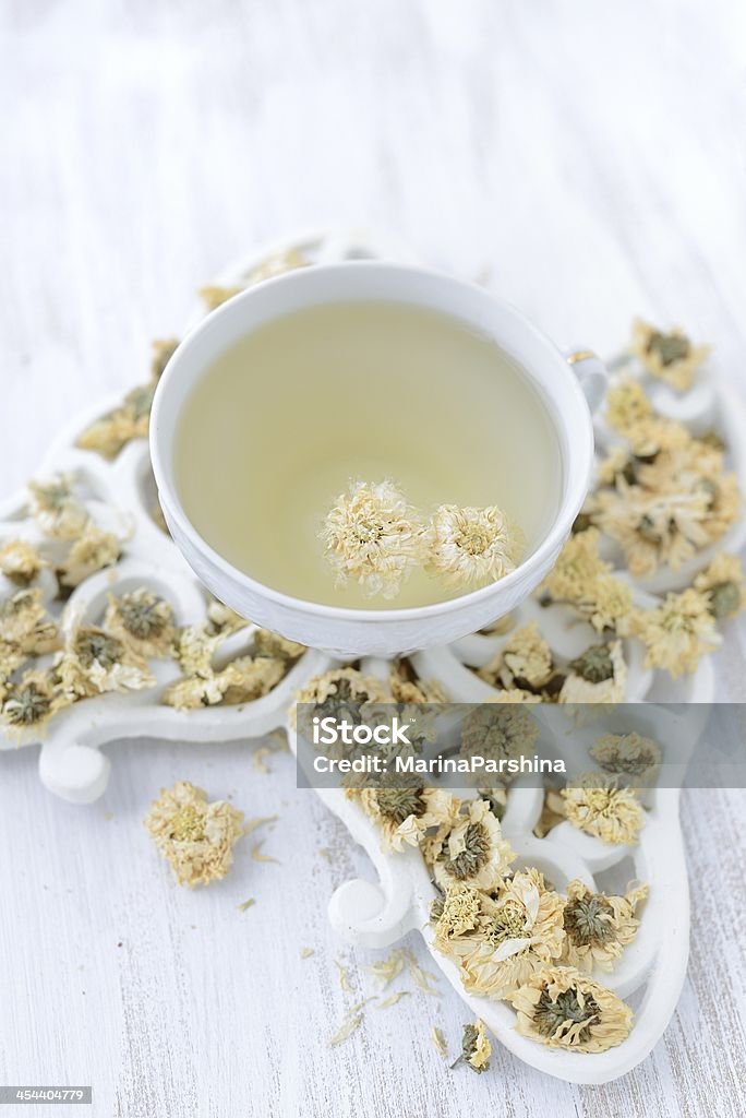 Chrysanthemumic tea Cup of chrysanthemumic tea stands on dried chrysanthemum flowers Dried Tea Leaves Stock Photo