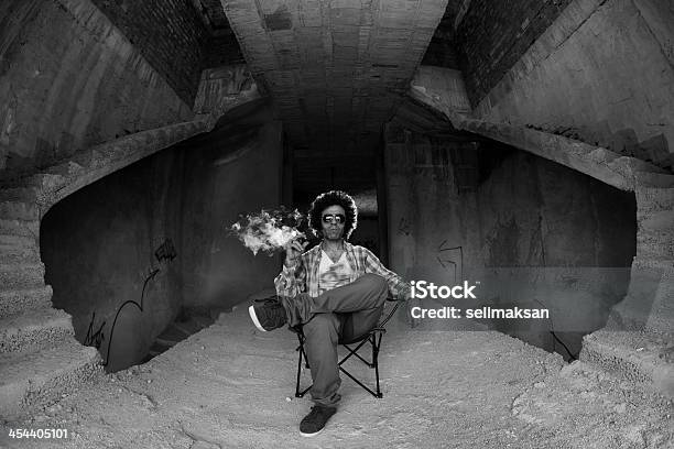 Funky Hombre Sentado En Abandonado Edificio Y Tabaquismo De Cigarrillos Foto de stock y más banco de imágenes de Abandonado