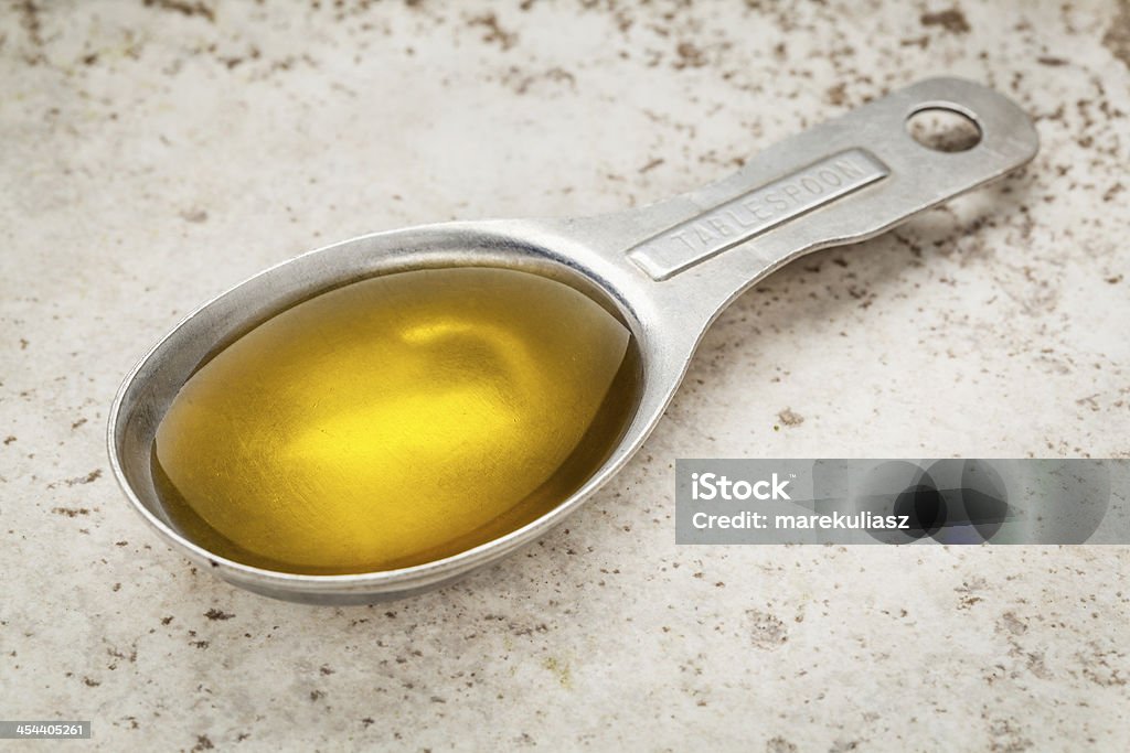 tablespoon of olive oil Measuring tablespoon of olive oil on a kitchen counter (ceramic tile) Olive Oil Stock Photo