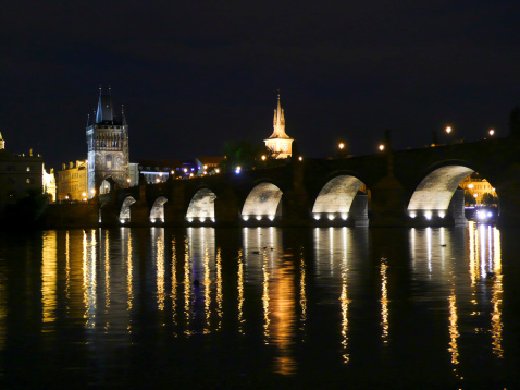 A view of Charles Bridge and the Old Town of Prague at night with reflections off the Vltava River. This is a romantic location to view the bridge.