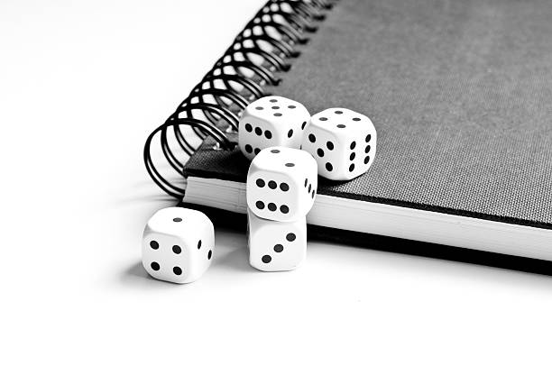 Black notebook with dices on white background stock photo