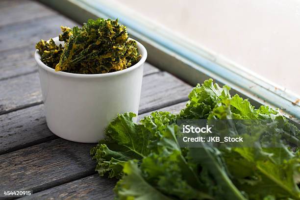 White Bowl Of Kale Chips Next To Fresh Kale By The Window Stock Photo - Download Image Now