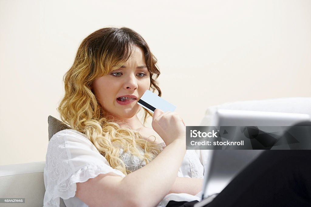 Nervioso Chica joven de compras en línea con tarjeta de crédito - Foto de stock de 18-19 años libre de derechos