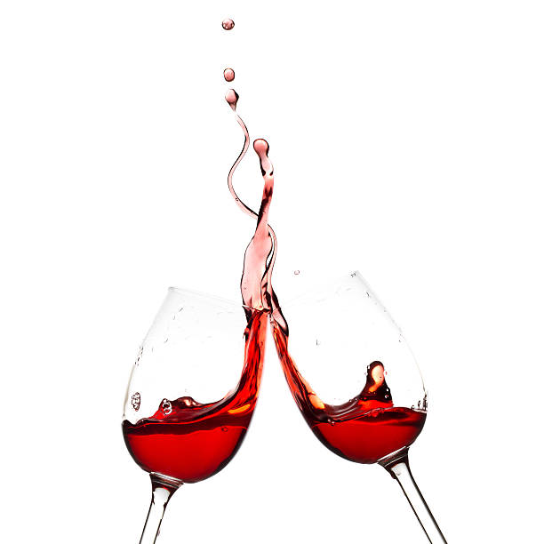 Wine glasses clinking together with red wine stock photo
