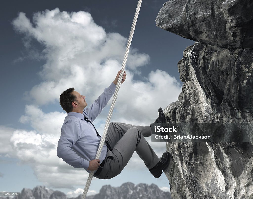 Businessman climbing mountain Business man climbs a mountain concept for challenge, conquering adversity and leadership Businessman Stock Photo