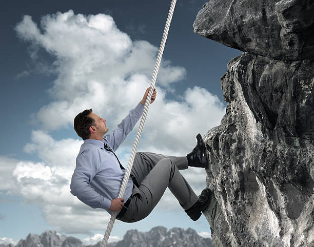 Businessman climbing mountain Business man climbs a mountain concept for challenge, conquering adversity and leadership clambering photos stock pictures, royalty-free photos & images