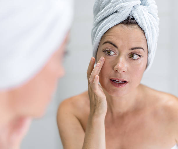 istock attractive middle aged woman looking in the mirror 454924107