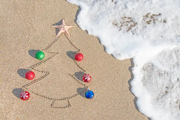 Christmas tree contour with decorations, star and wave on the beach - holiday vacation concept