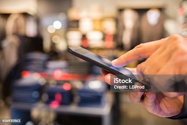 Man Using Mobile Phone In Clothing Store Stock Photo - Download Image Now - Adult, Adults Only, Business