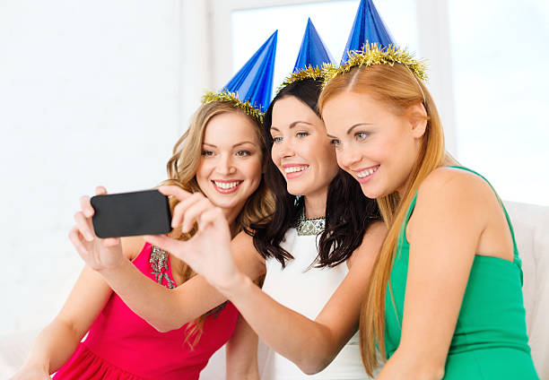 istock three smiling women in hats having fun with camera 454937841